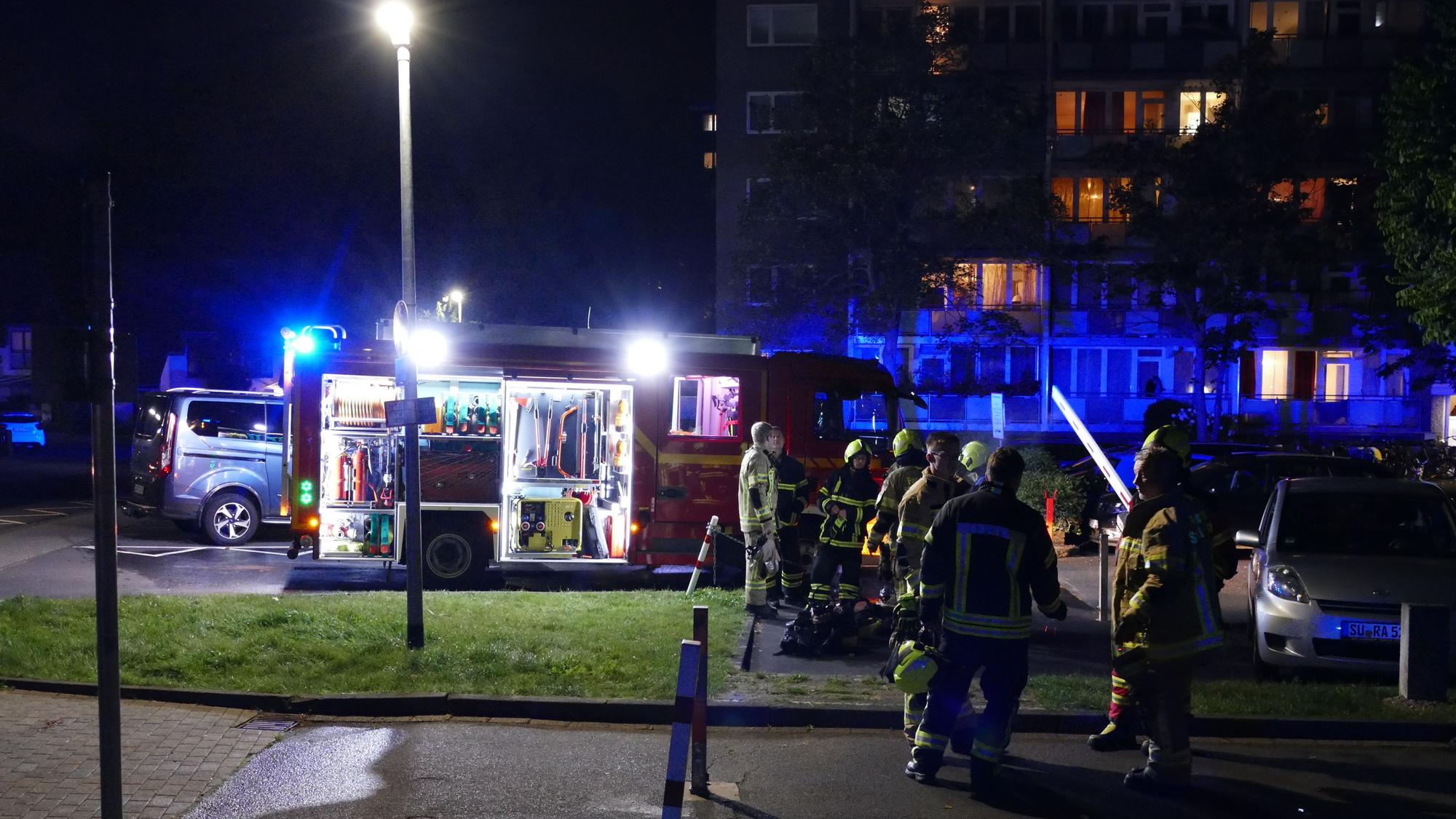 Feuerwehrleute stehen vor dem betroffenen Hochhaus in Niederpleis.