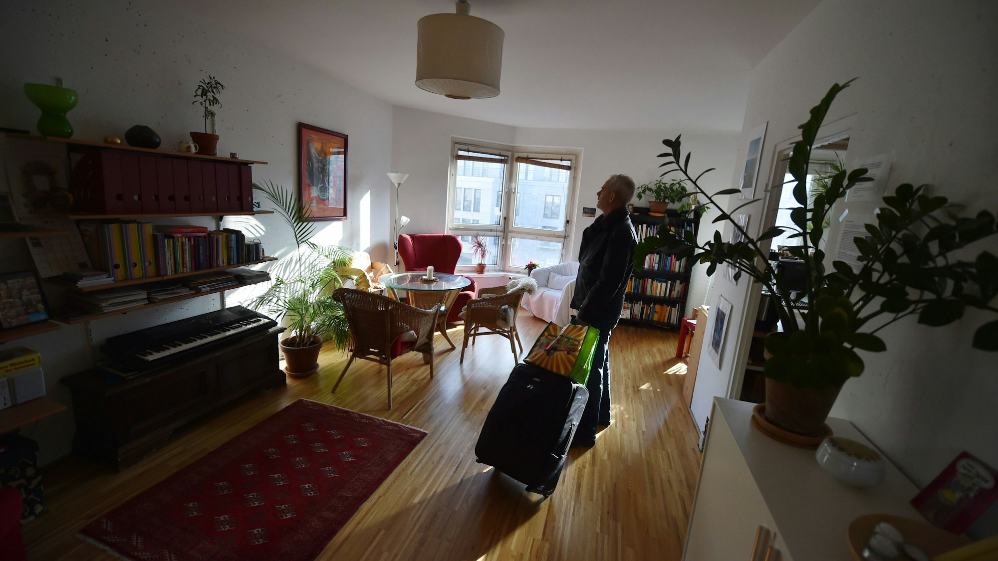 ARCHIV - ILLUSTRATION - Ein Tourist, der eine Übernachtung über das Onlineportal Airbnb gebucht hat, kommt am 07.11.2014 in Berlin mit seinem Koffer in der gemieteten Wohnung an. Online-Portale bieten individuelle Alternativen zur Pauschalreise. Auch in Sachsen-Anhalt wächst der Trend. Foto: Jens Kalaene/dpa (zu dpa-KORR lah "Zu Gast bei Fremden: Hotelalternativen werden beliebter im Land" vom 22.03.2015) +++ dpa-Bildfunk +++