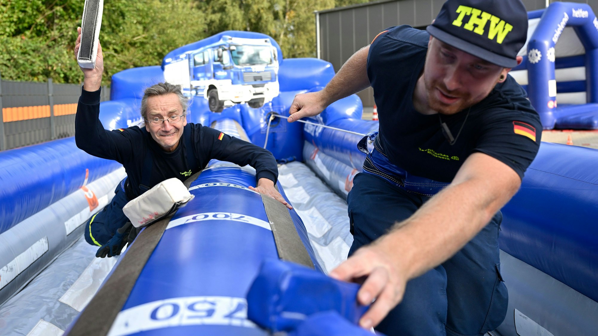 Zwei Männer laufen, angeleint an ein Gummiband, durch einen Luftburggang.