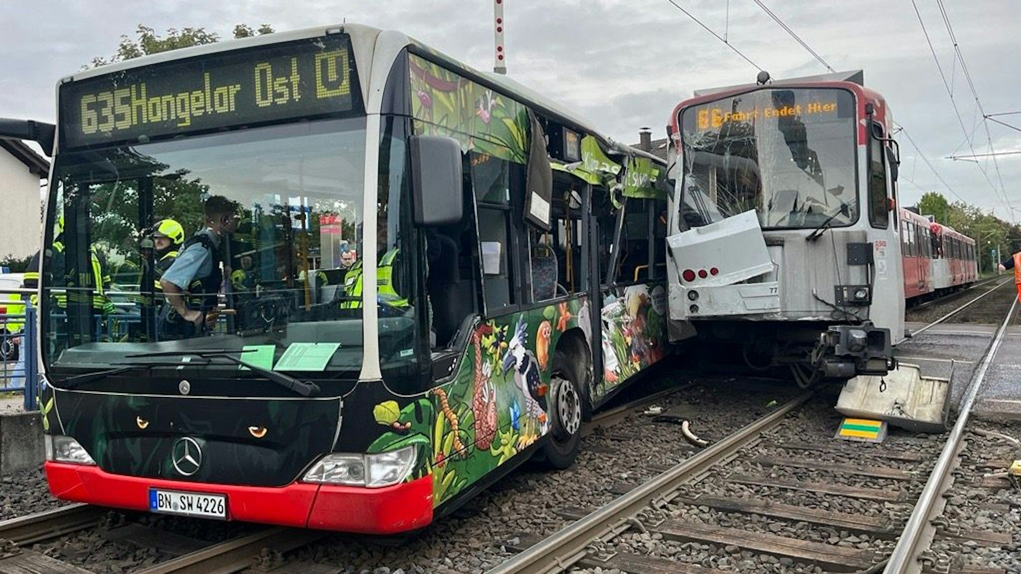 Ein Bus und eine Straßenbahn stehen auf dem Gleisbett, beide haben Schäden an den Seiten, wo sie ineinander geprallt sind.