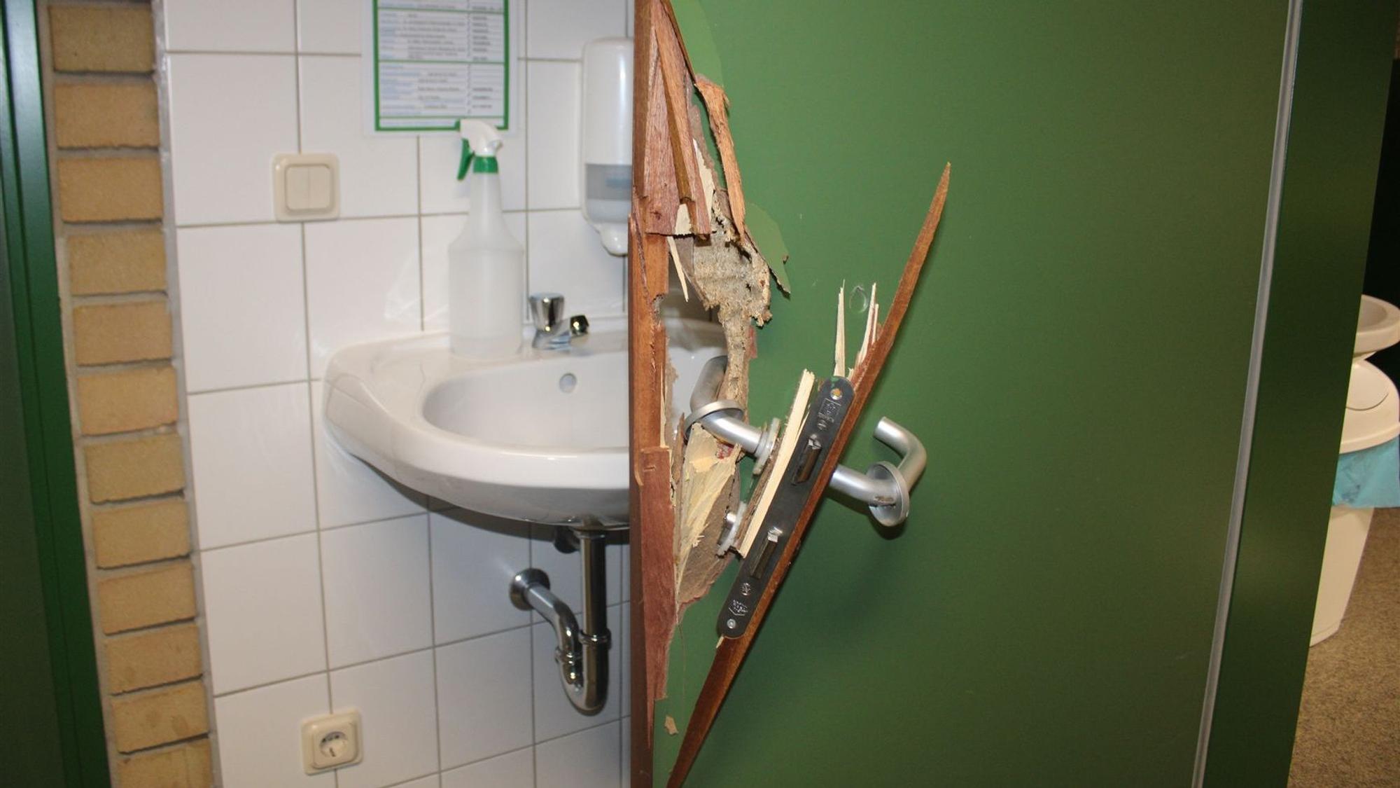 Eine grüne Tür wurde aufgebrochen, Klinke und Schloss sind herausgebrochen, ein Loch klafft im Holz.