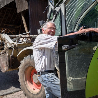 Heinrich Portz steigt auf seinem Hof von einem Traktor.