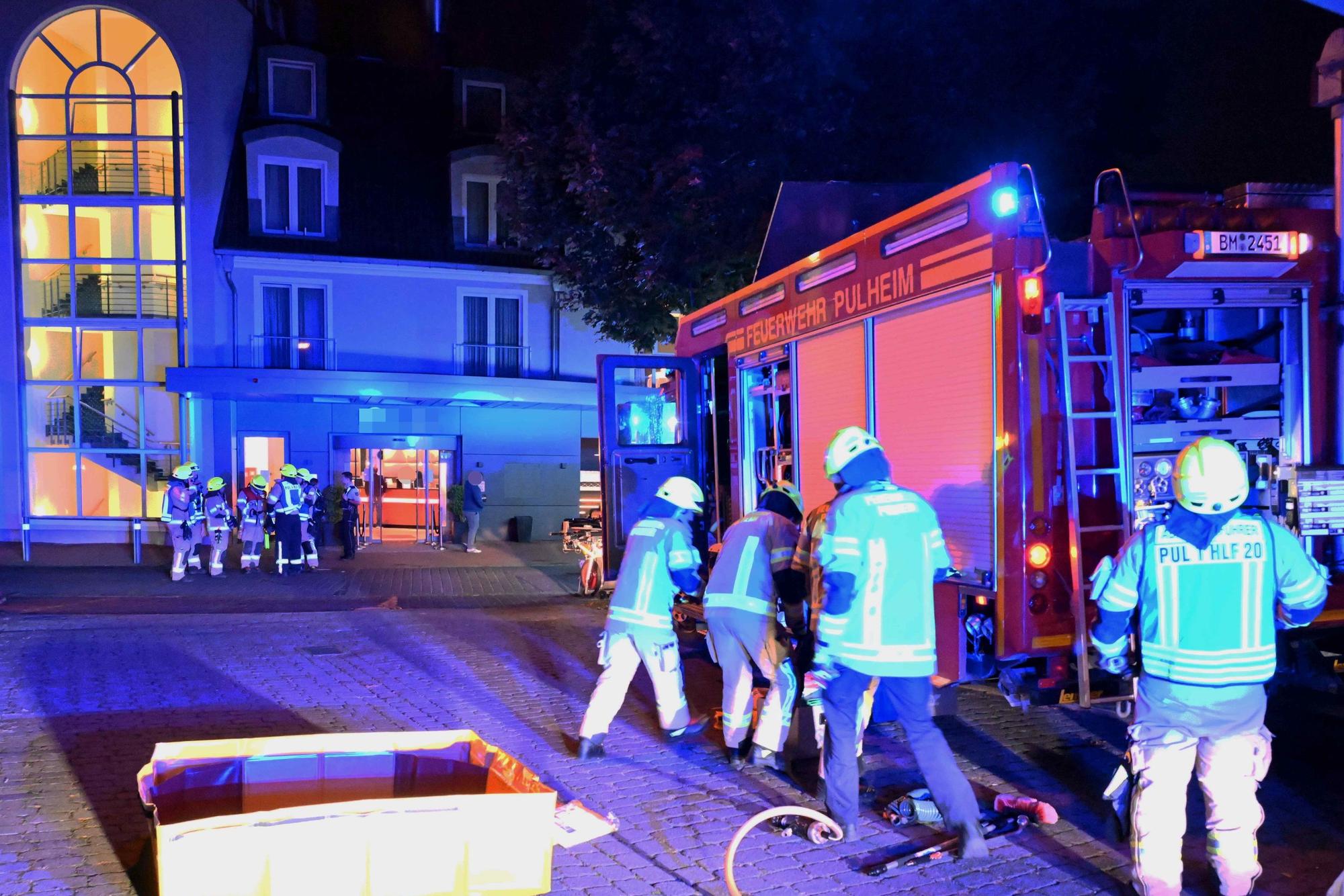 Das Bild zeigt mehrere Einsatzkräfte an einem Feuerwehrfahrzeug vor dem Hotel.