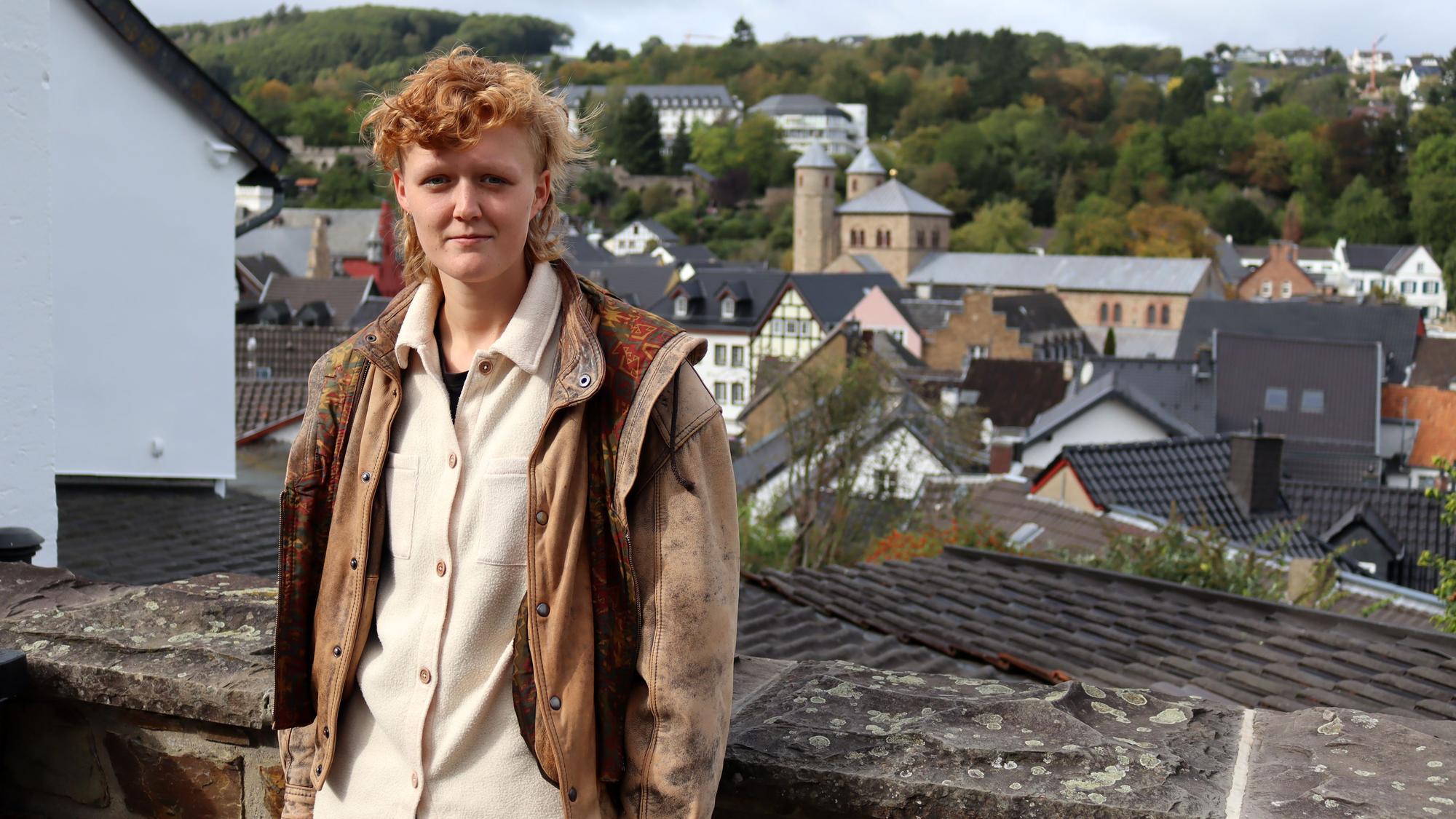 Die Schauspielerin und Musikerin Svea Kirschmeier lehnt an einer hüfthohnen Bruchsteinmauer. Hinter ihr die ist Kulisse Bad Münstereifels zu erkennen.
