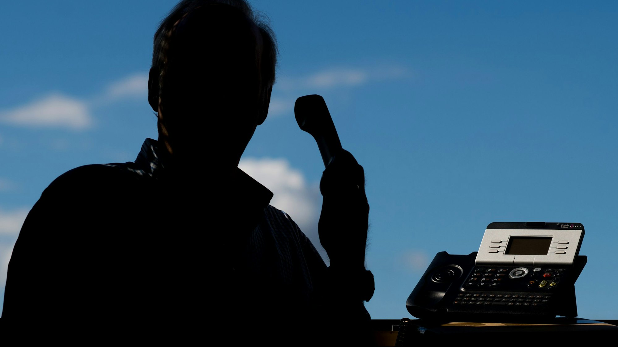 Das Bild zeigt einen Mann an einem Telefon.