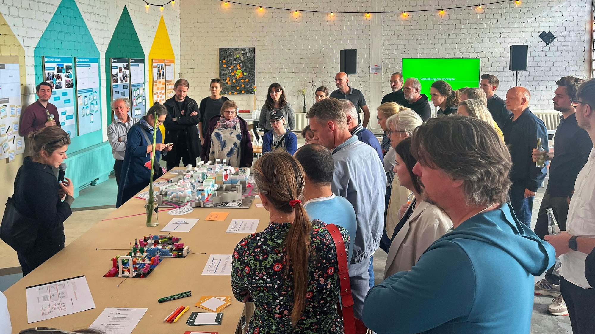 Viele Menschen stehen um einen großen Tisch, auf dem ein Modell aufgebaut ist.