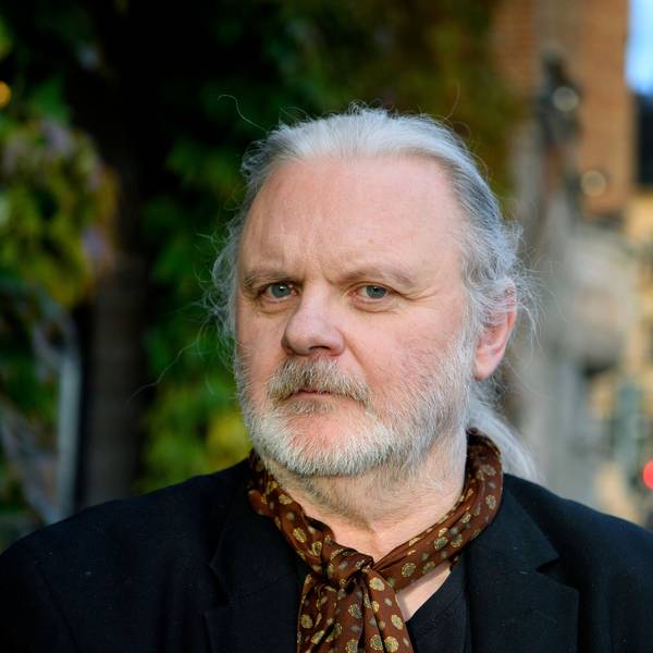 Der norwegische Schriftsteller Jon Fosse posiert für ein Foto in Stockholm. Er hat lange weiße Haare, die er sich hinten zusammengebunden hat, einen Bart, und trägt einen braunen gepunkteten Schal.