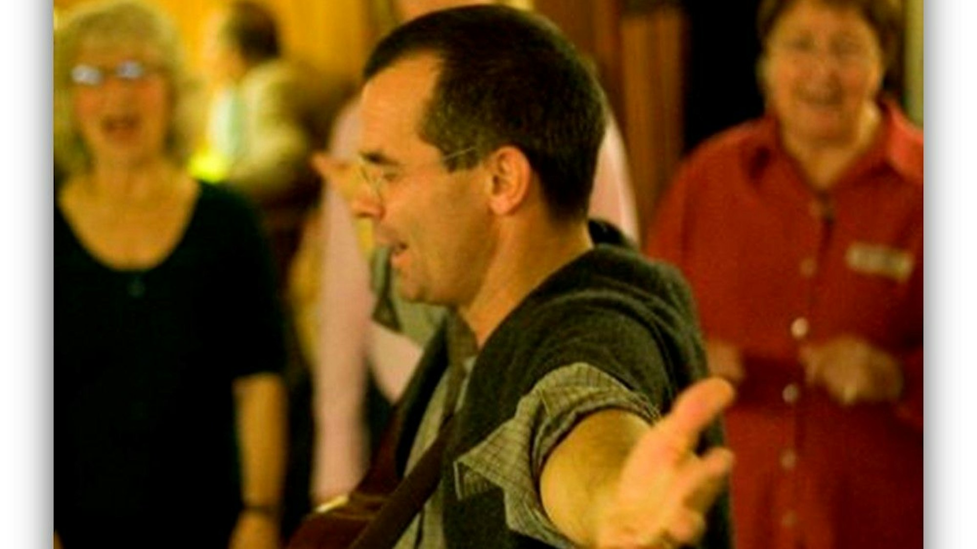 Ein Mann mit ausgebreiteten Armen vor einem Chor.