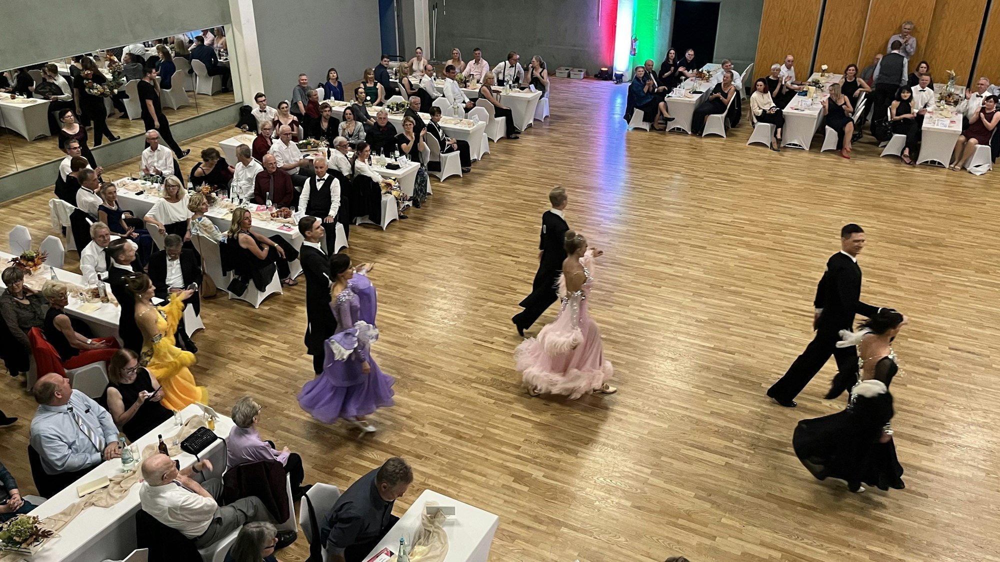 Tanzpaare laufen auf eine Tanzfläche aus Parkett.