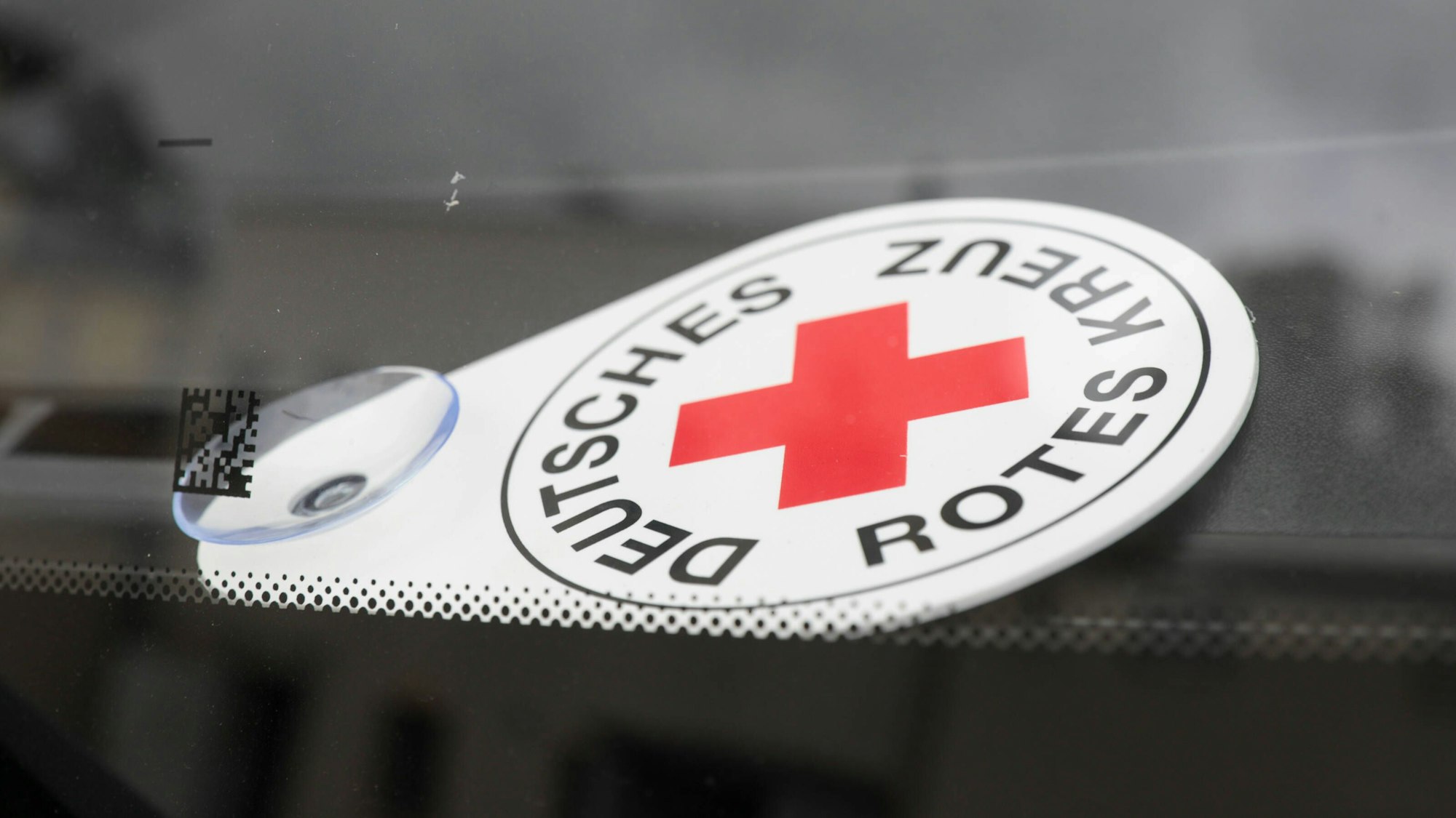 Autoschild Deutsches Rotes Kreuz liegt hinter der Frontscheibe eines Fahrzeuges des Katastrophenschutzes.