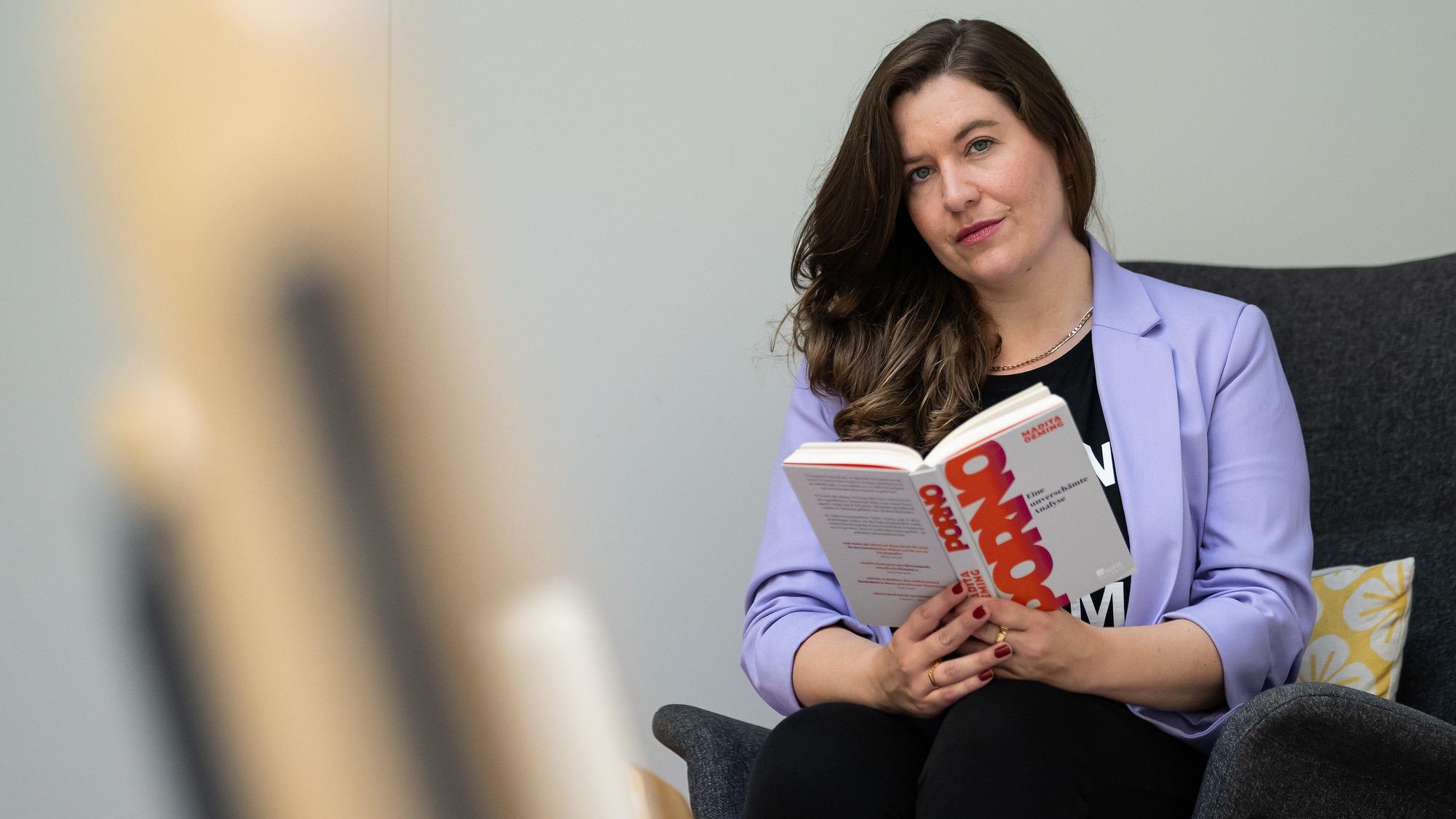 Die unabhängige Pornowissenschaftlerin Madita Oeming sitzt mit ihrem neuen Buch "Porno. Eine unverschämte Analyse" auf einem Sessel.