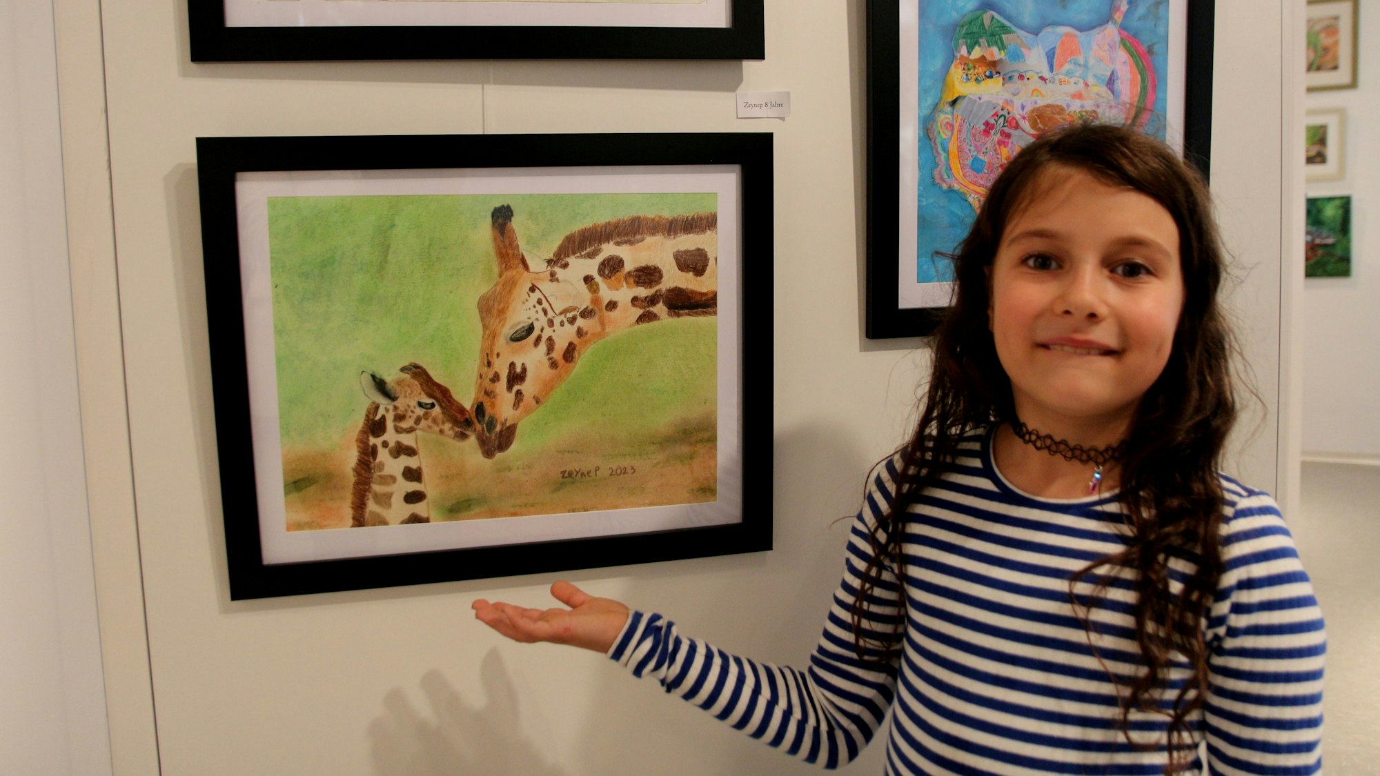 Ein Mädchen zeigt auf ein Bild, auf dem Giraffen zu sehen sind.