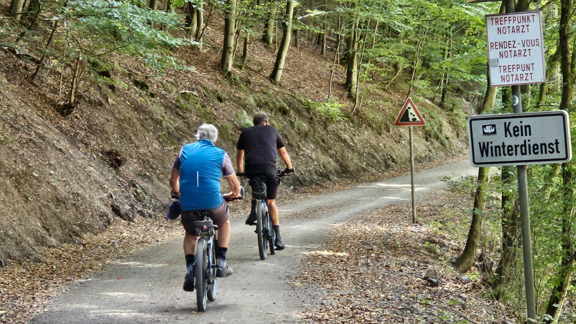 Zwei Radfahrer sind auf dem Weg unterwegs.