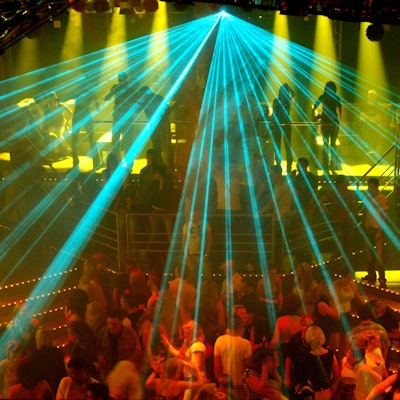 Eine Laseranlage beleuchtet eine tanzende Menschenmenge in einer Großraumdiscothek.