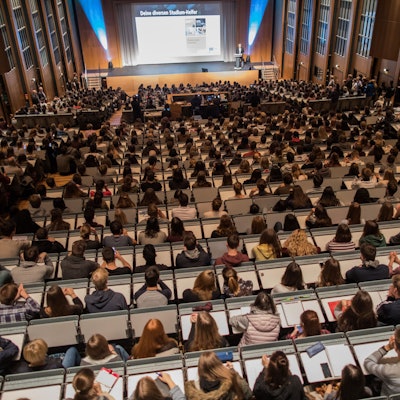 Studenten verfolgen im Hörsaal im Hauptgebäude der Universität zu Köln die Erstsemesterbegrüßung.