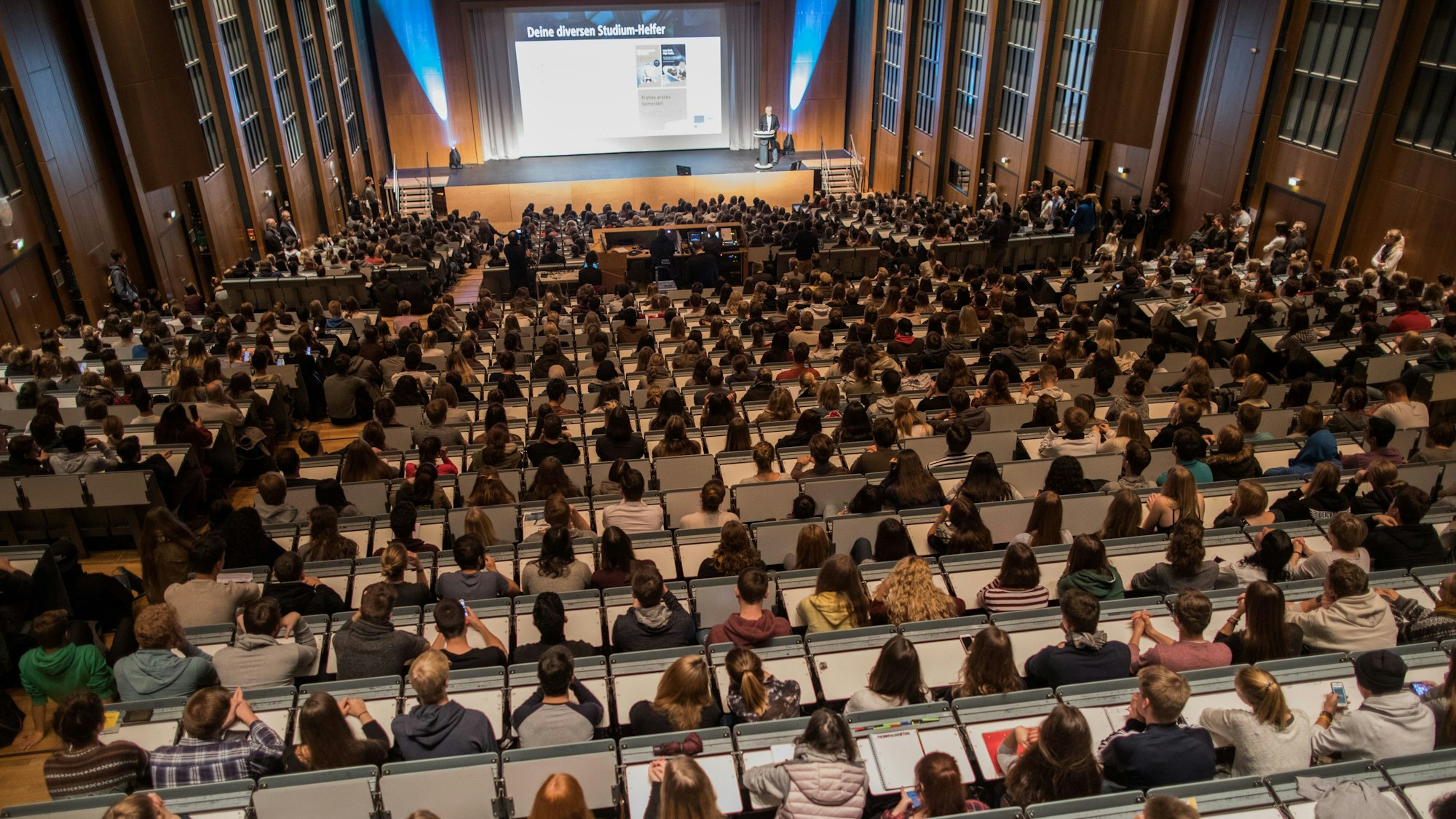 Studenten verfolgen im Hörsaal im Hauptgebäude der Universität zu Köln die Erstsemesterbegrüßung.