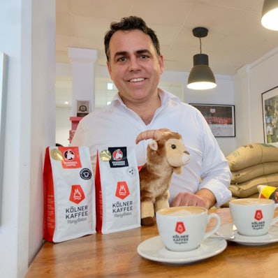 Kaffeeröster Gregor Hempsch steht an einem Tisch mit Kaffee.