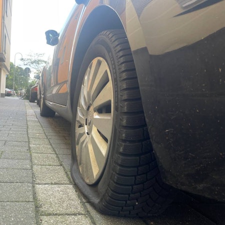 Parkendes Auto mit einem zerstochenen Reifen
