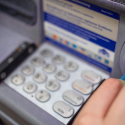 Eine Bankkundin steckt ihre Girokarte in einen Geldautomaten.