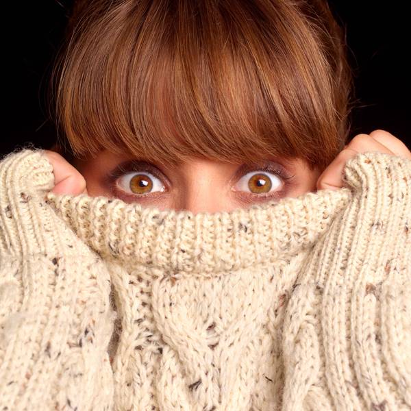 Junge Frau verkriecht sich in bis über die Nase in ihrem Pullover