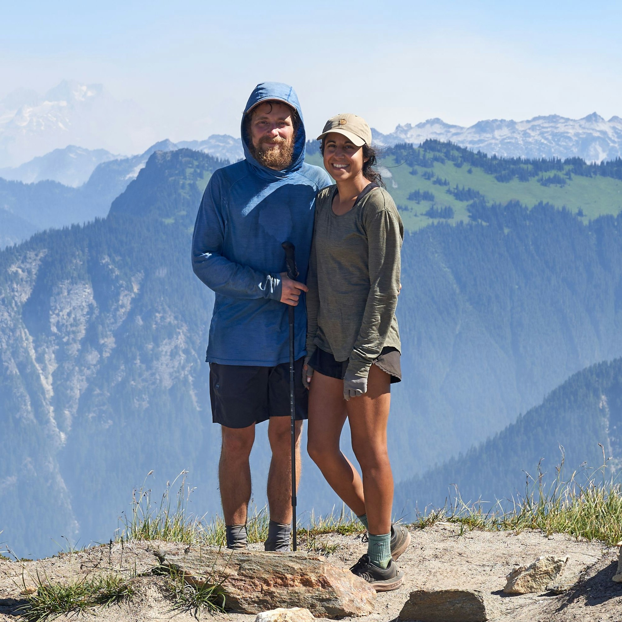 Die beiden Wanderer David Flitsch und Miriam Wiesner schauen vor einem Bergmassiv in die Kamera.