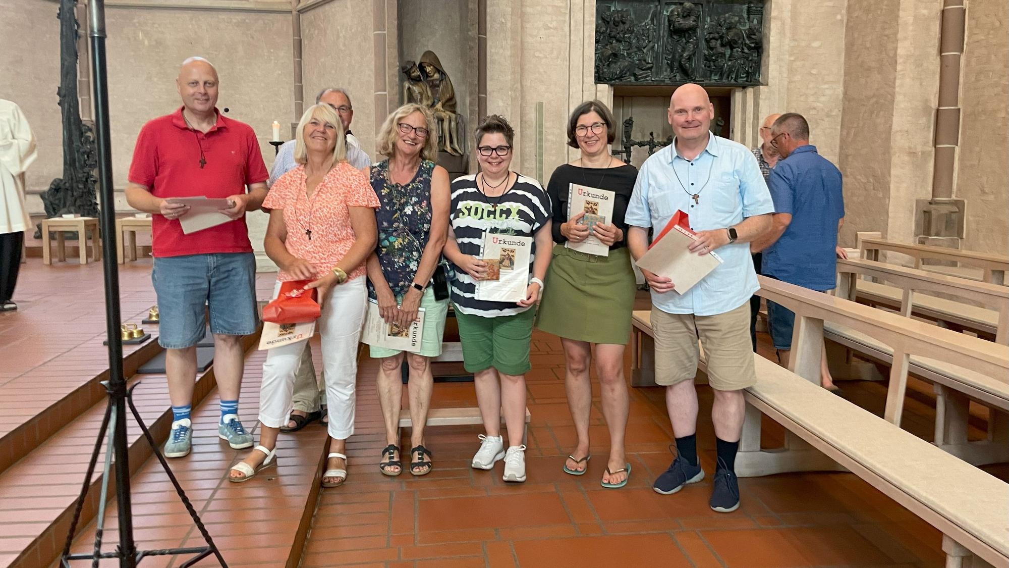 Pilger-Jubilare stehen mit ihrer Urkunde in der Hand für ein Gruppenfoto in einer Kirche.