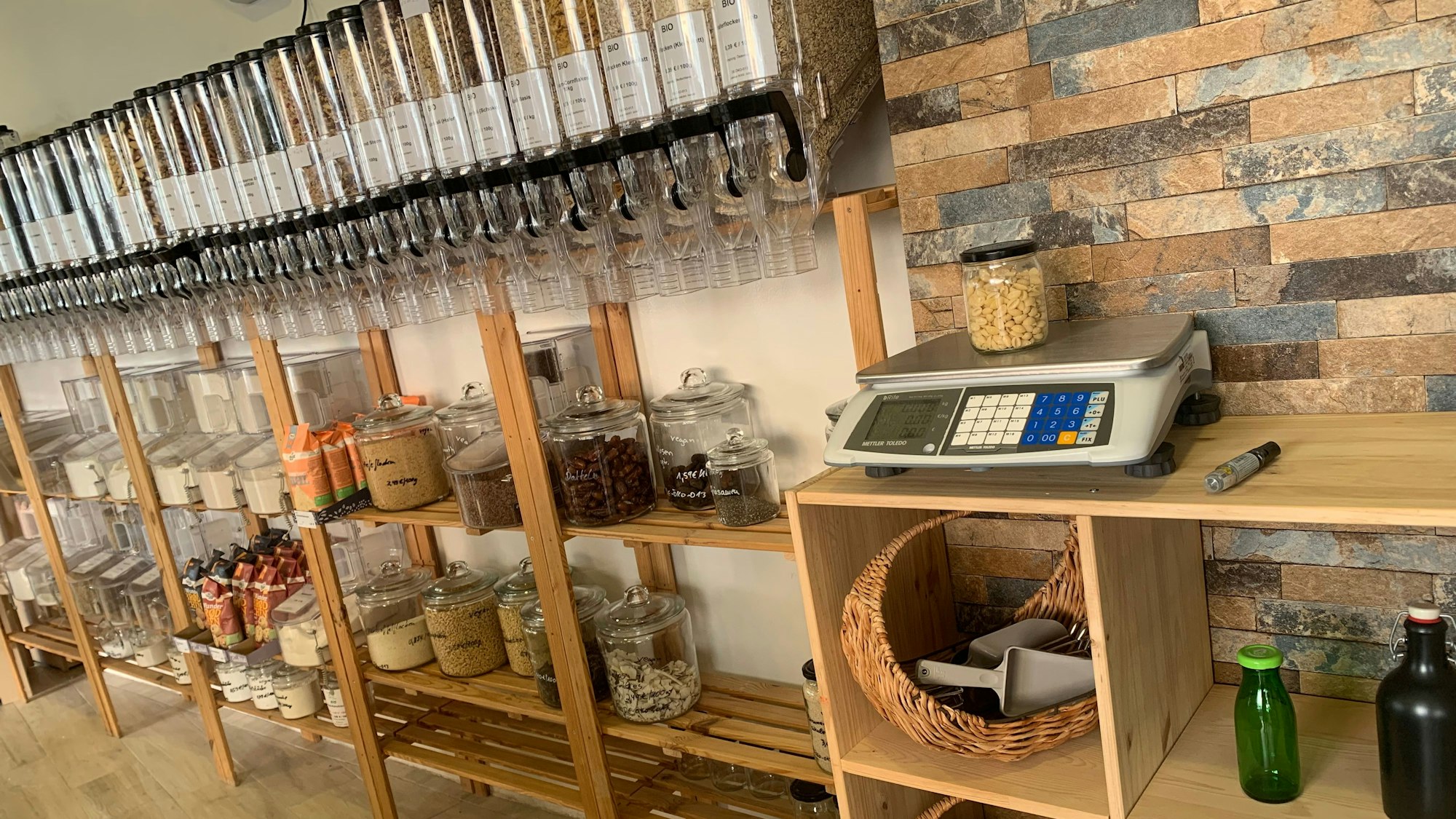 Lnks die Abfüllstation im Unverpackt-Laden in Troisdorf. Rechts die Waage auf einem Regal. Ein Fach ist für Gefäße reserviert, die Kunden spenden können.