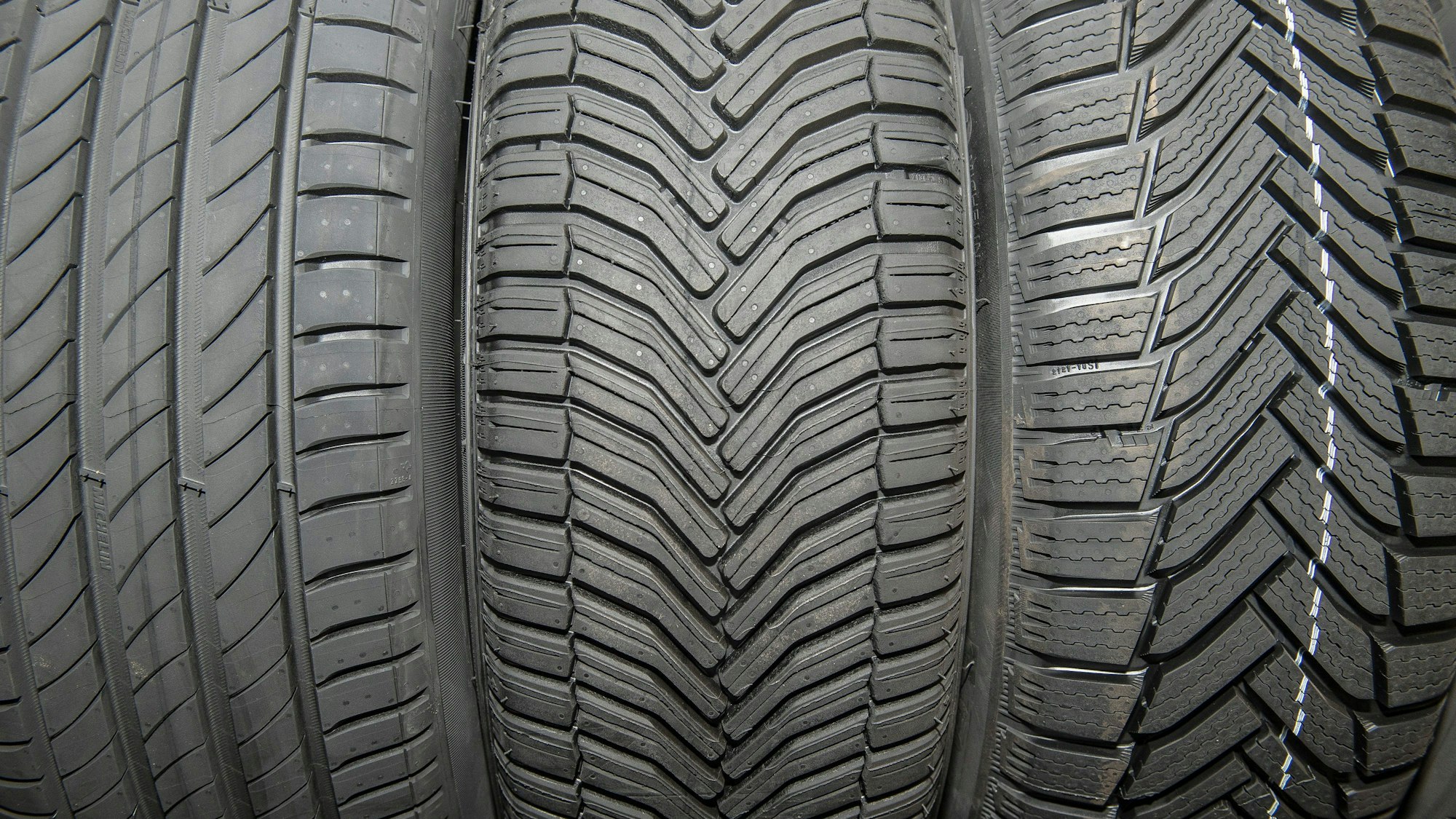 Links sind Sommerreifen, in der Mitte Allwetterreifen und rechts Winterreifen zu sehen. Die Winterreifen haben ein deutlich tieferes Profil