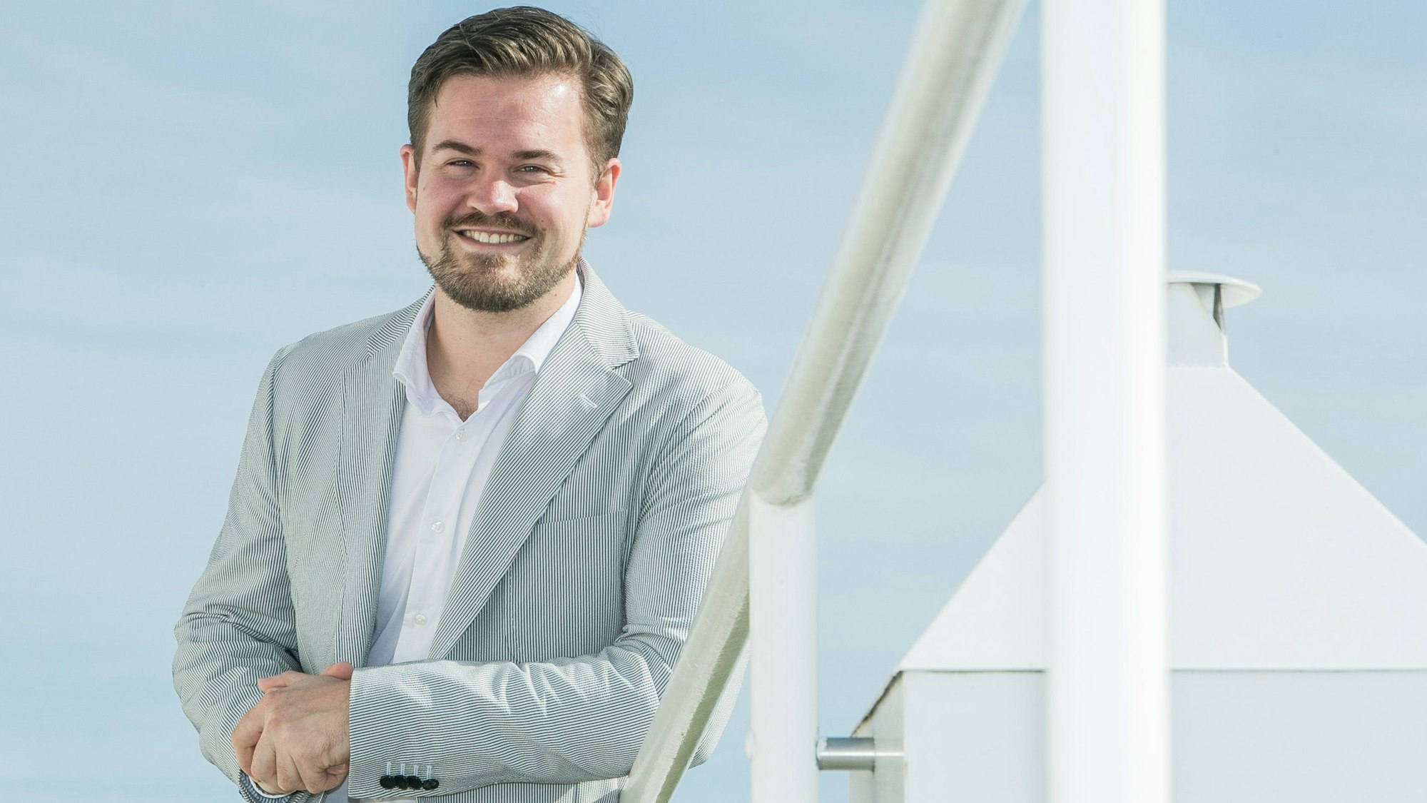 Bild eines Mannes, im Hintergrund ein großes weißes Kreuz.