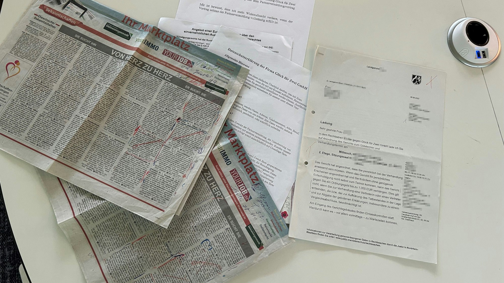 Die Zeitungsseite und die Unterlagen aus dem Rechtsstreit mit der Glück für Zwei GmbH.