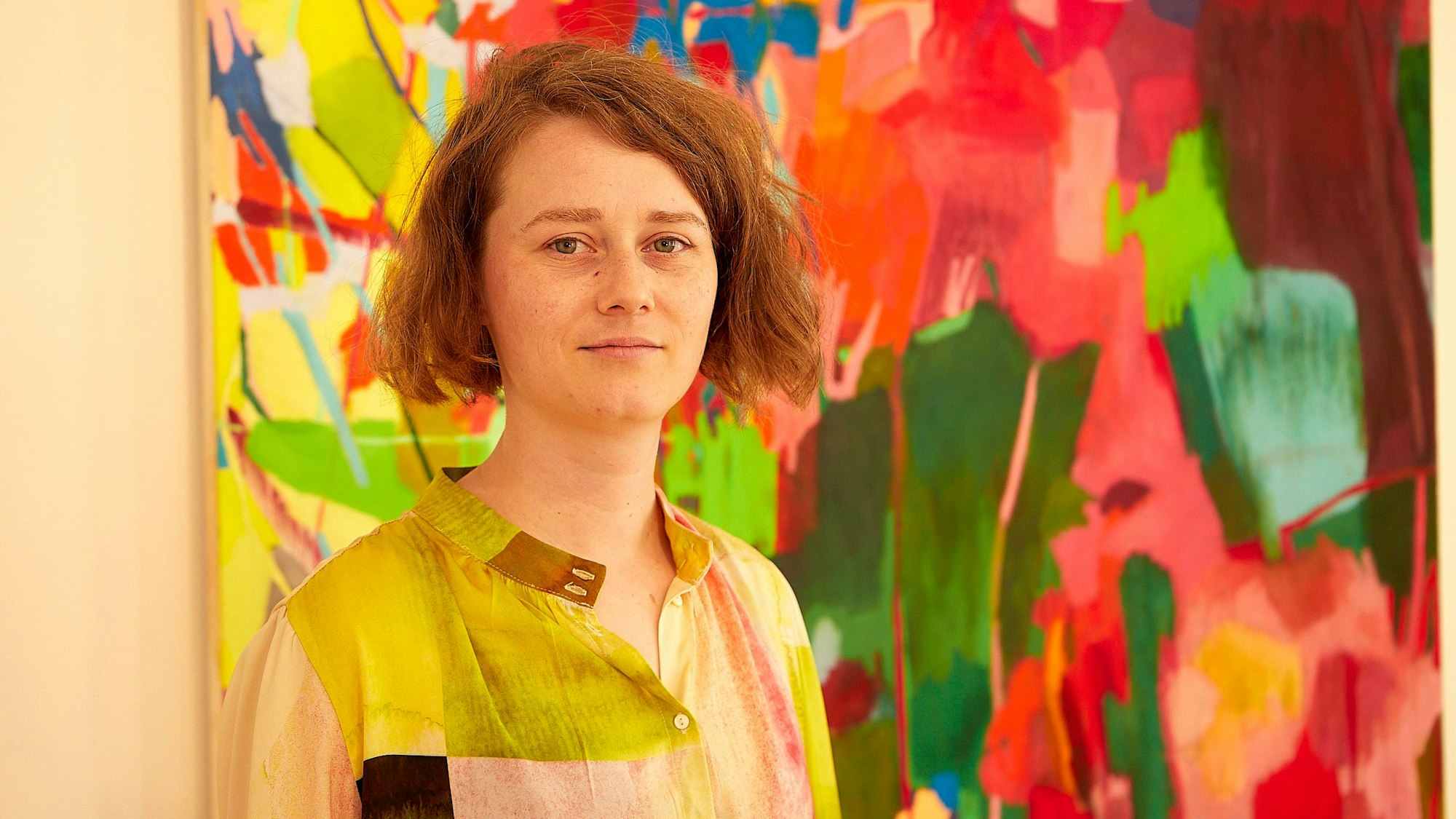 Die Künstlerin Mirjam Baker steht vor einem ihrer Gemälde, die im Kuba in Nettersheim zu sehen sind.