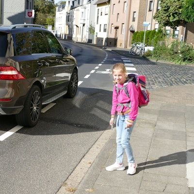 Ein Mädchen steht an einer befahrenen Straße.