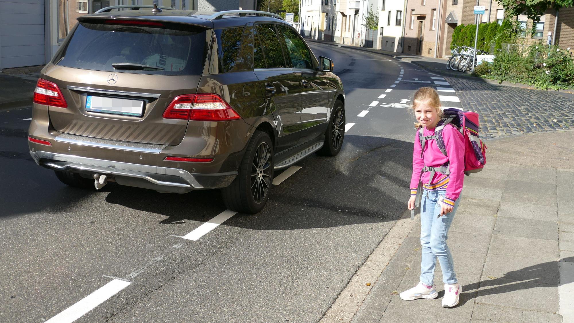 Ein Mädchen steht an einer befahrenen Straße.