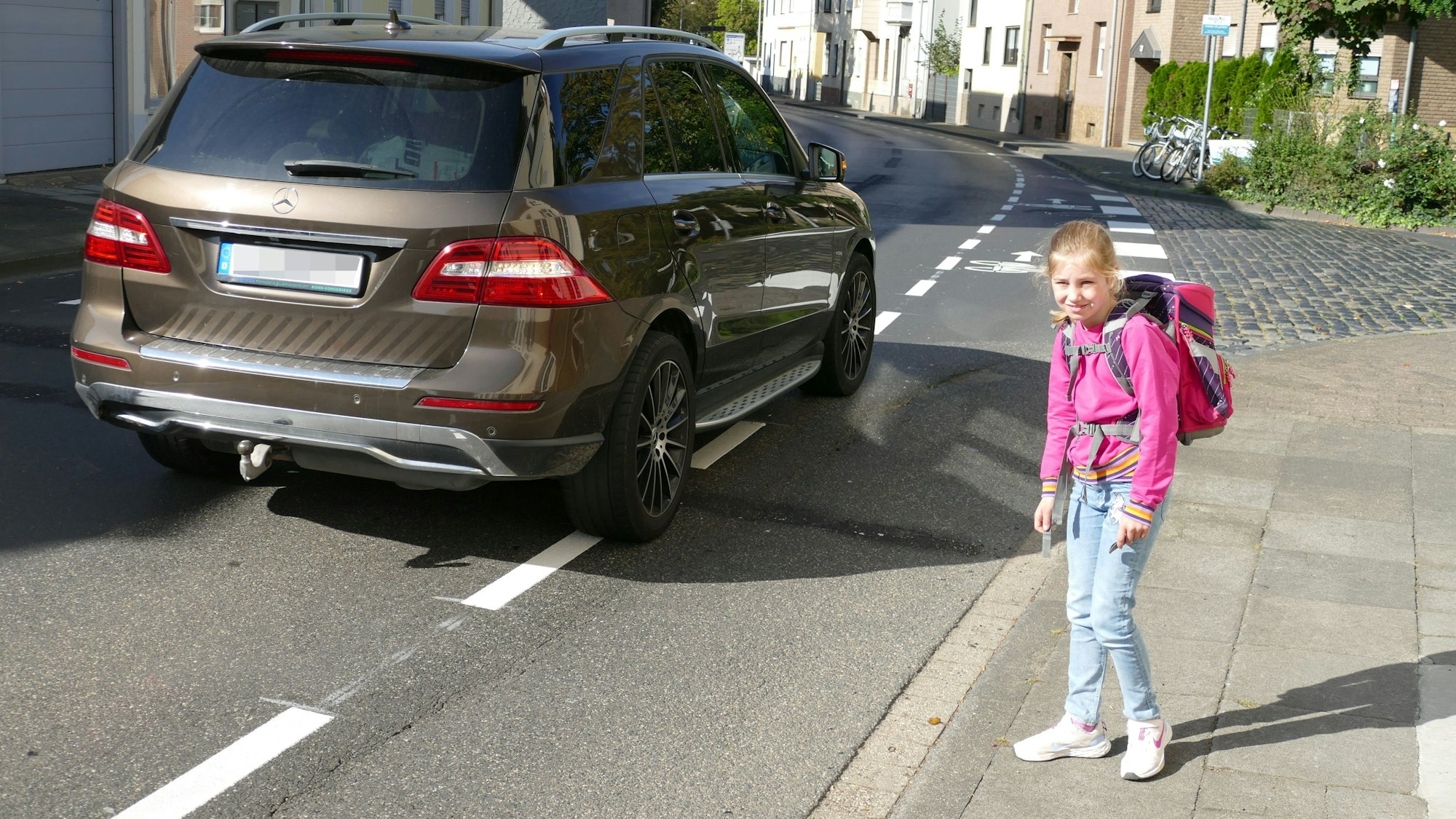 Ein Mädchen steht an einer befahrenen Straße.