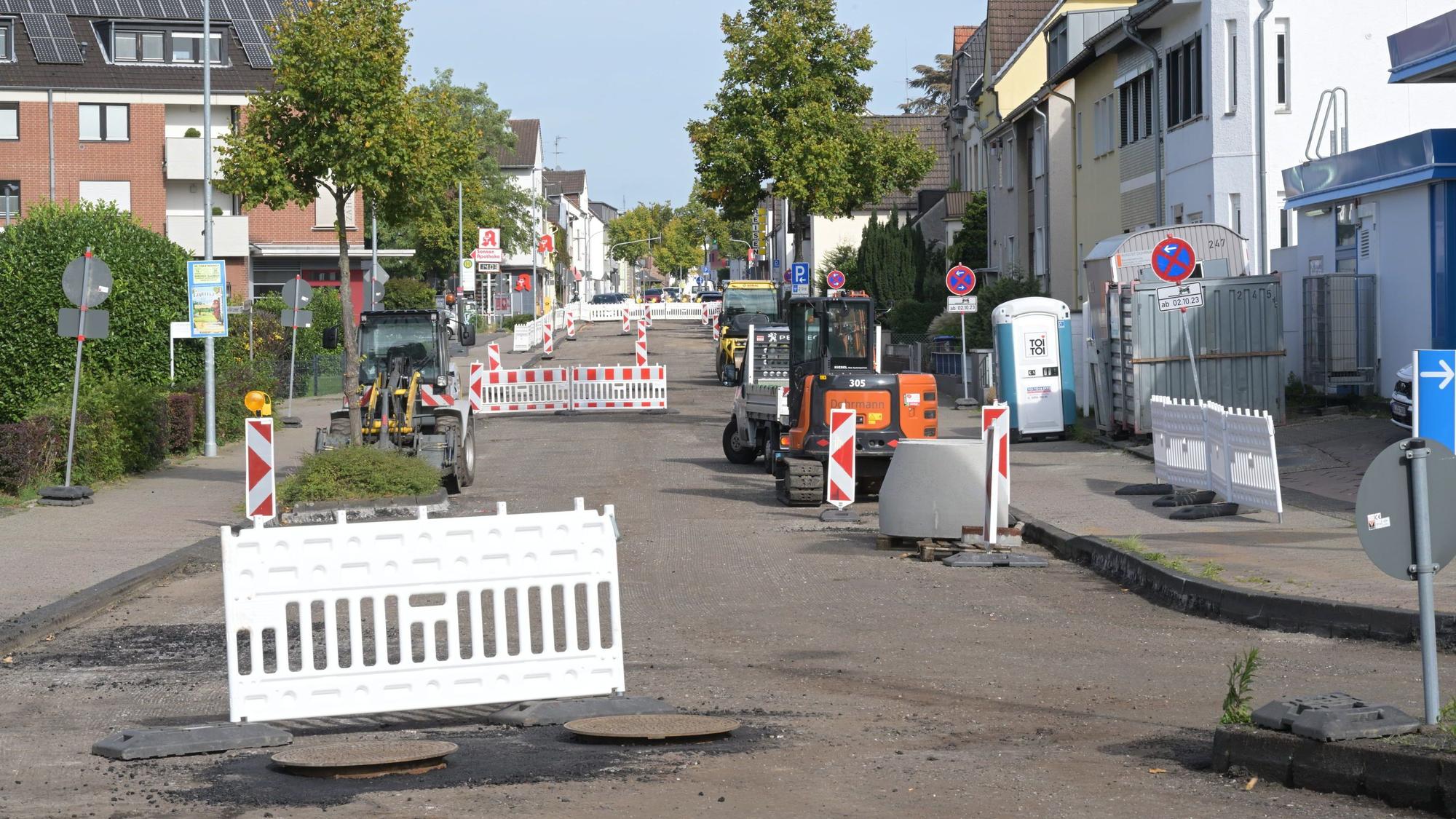 Warnbaken stehen auf einer Straße, deren Oberfläche abgefräst ist.