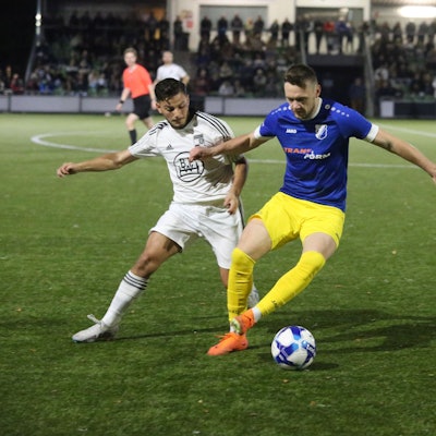 Zwei gegnerische Fußballspieler in Kampf um den Ballgewinn.
