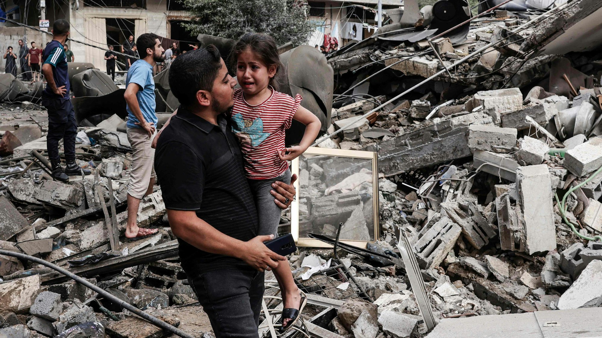 Ein Mann trägt ein Kind nach dem Gegenschlag der israelischen Luftwaffe im Gaza-Streifen. Der Terror der Hamas ruft Reaktionen Israels hervor, die Folge sind auch viele zivile Opfer.