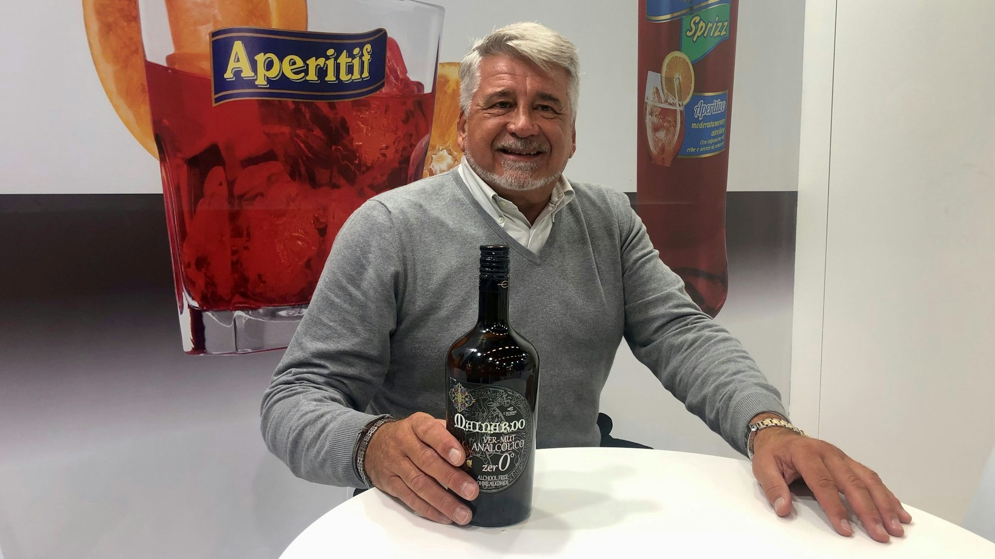 Grauhaariger Mann präsentiert einen alkoholfreien Vermouth