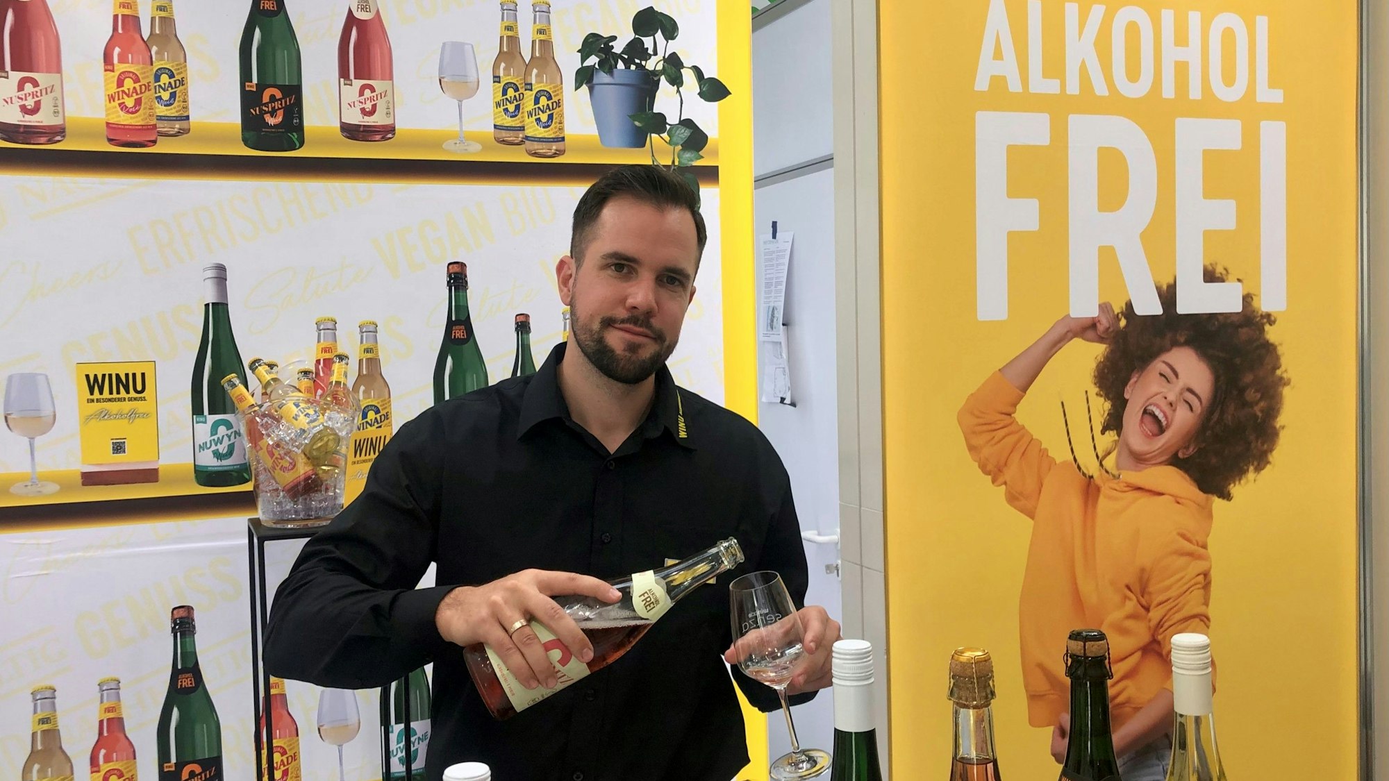 Junger bärtiger Mann schenkt ein Glas Wein ein