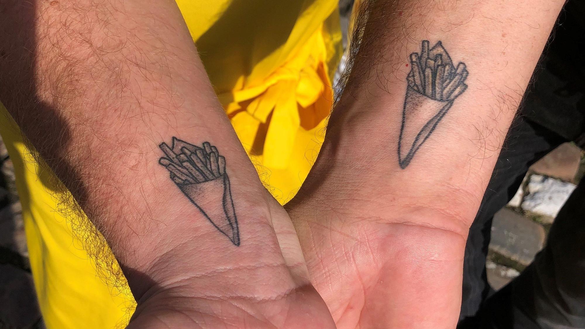 Die beiden belgischen Gastronomen Fabian Frances (l) und Sébastian Viloria (r) haben sich eine Pommes-frites-Tüte auf das Handgelenk tätowieren lassen.