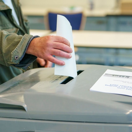 Ein Mann wirft seinen Stimmzettel in die Wahlurne.