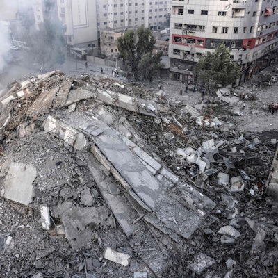 TOPSHOT - People walk around the ruins of a building destroyed in Israeli airstrikes in Gaza City on October 8, 2023. Fighting between Israeli forces and the Palestinian militant group Hamas raged on October 8, with hundreds killed on both sides after a surprise attack on Israel prompted Prime Minister Benjamin Netanyahu to warn they were "embarking on a long and difficult war". (Photo by Mohammed ABED / AFP)