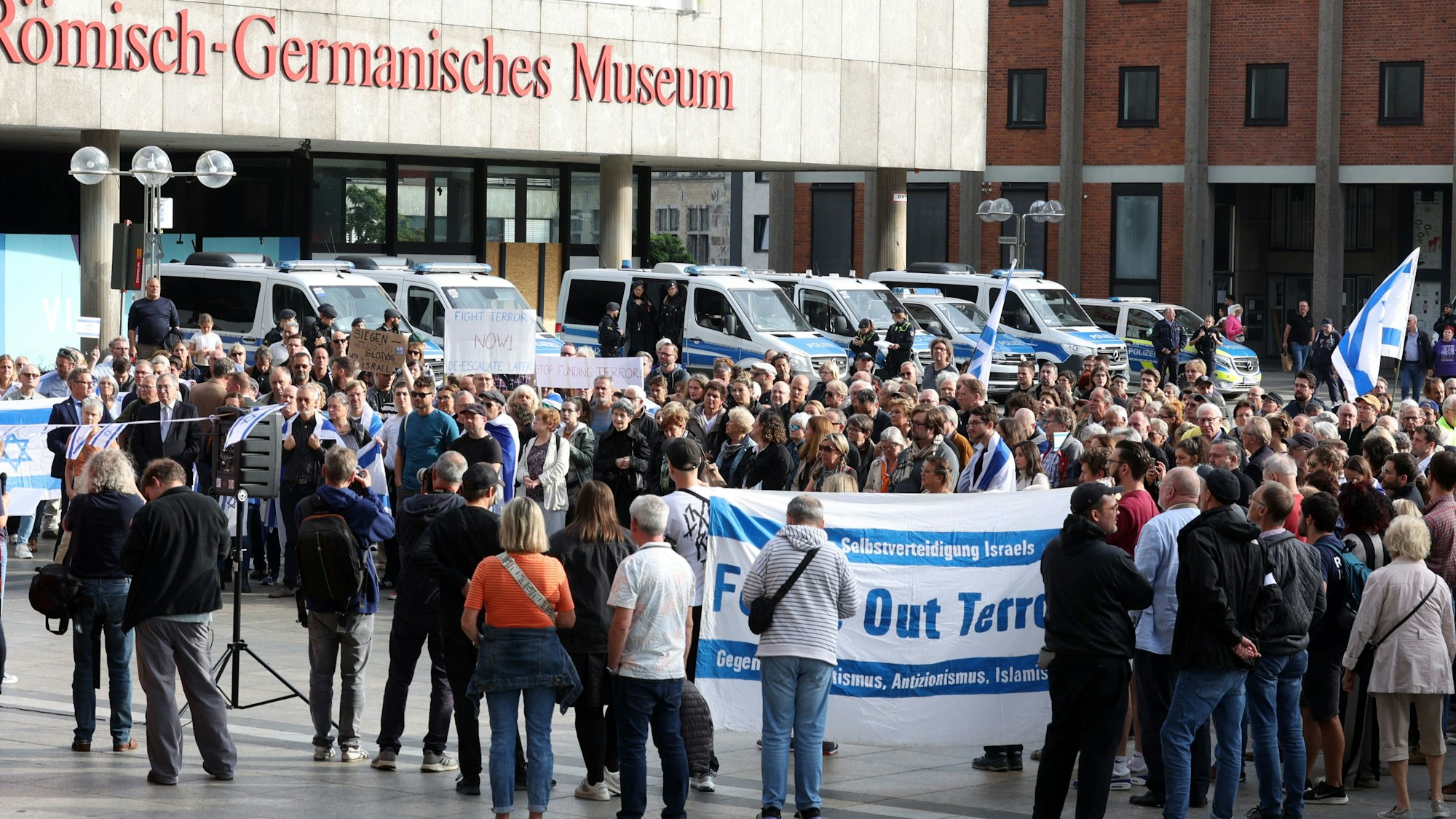 Israel-Unterstützer schwenken Fahnen und ein Transparent bei einer Kundgebung auf dem Roncalliplatz.