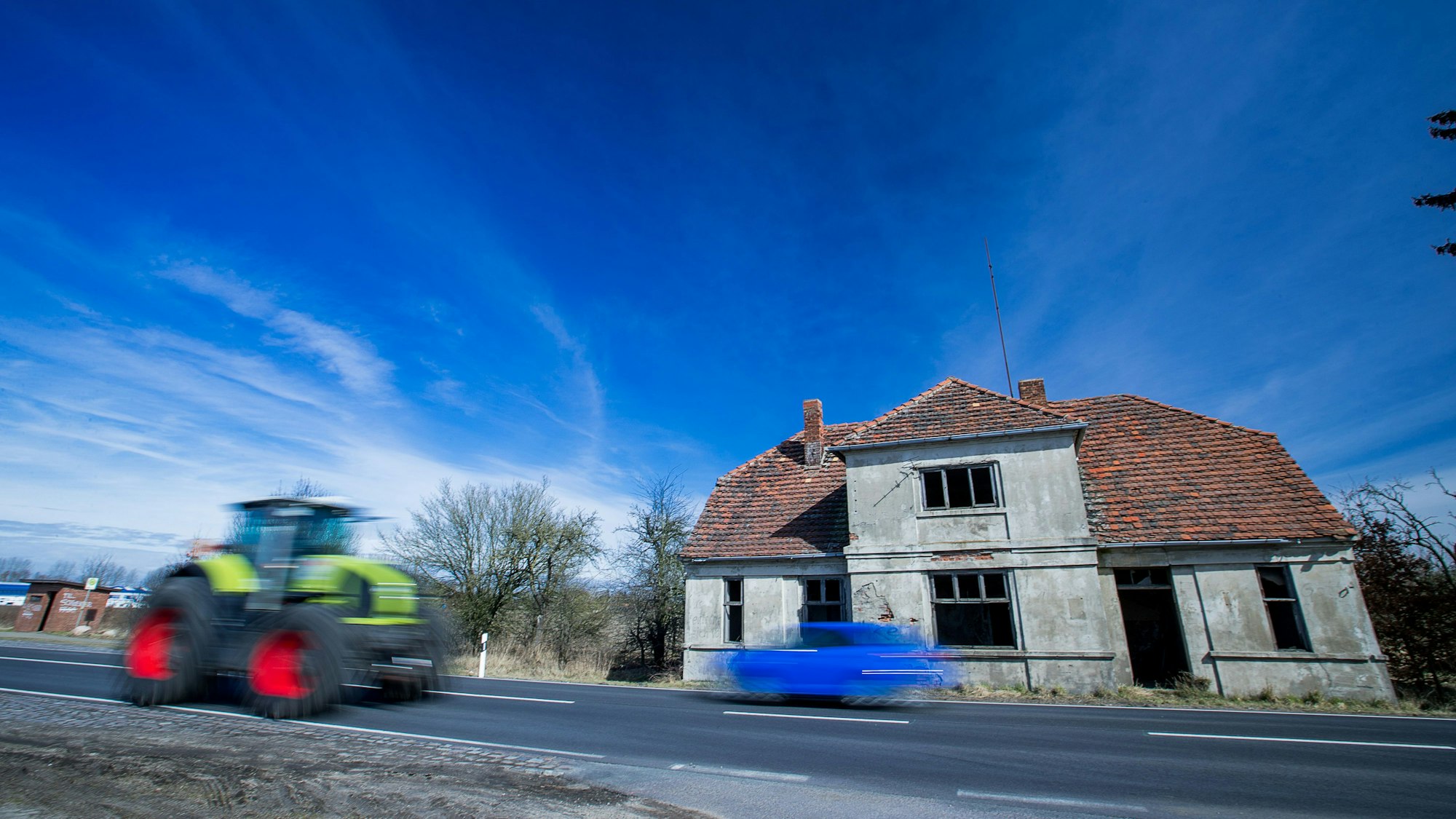 Ein Traktor fährt an einem leerstehenden und verfallenen Wohnhaus an der Bundesstraße 5 in Kremmin vorbei. Nach Prognosen des Instituts der deutschen Wirtschaft (IW) wird die Bevölkerungzahl im Nordosten bis 2035 um 4,8 Prozent zurückgehen. Mit rund 77.000 weniger Menschen verzeichnet Mecklenburg-Vorpommern dann den viertgrößten Bevölkerungsschwund aller Bundesländer.