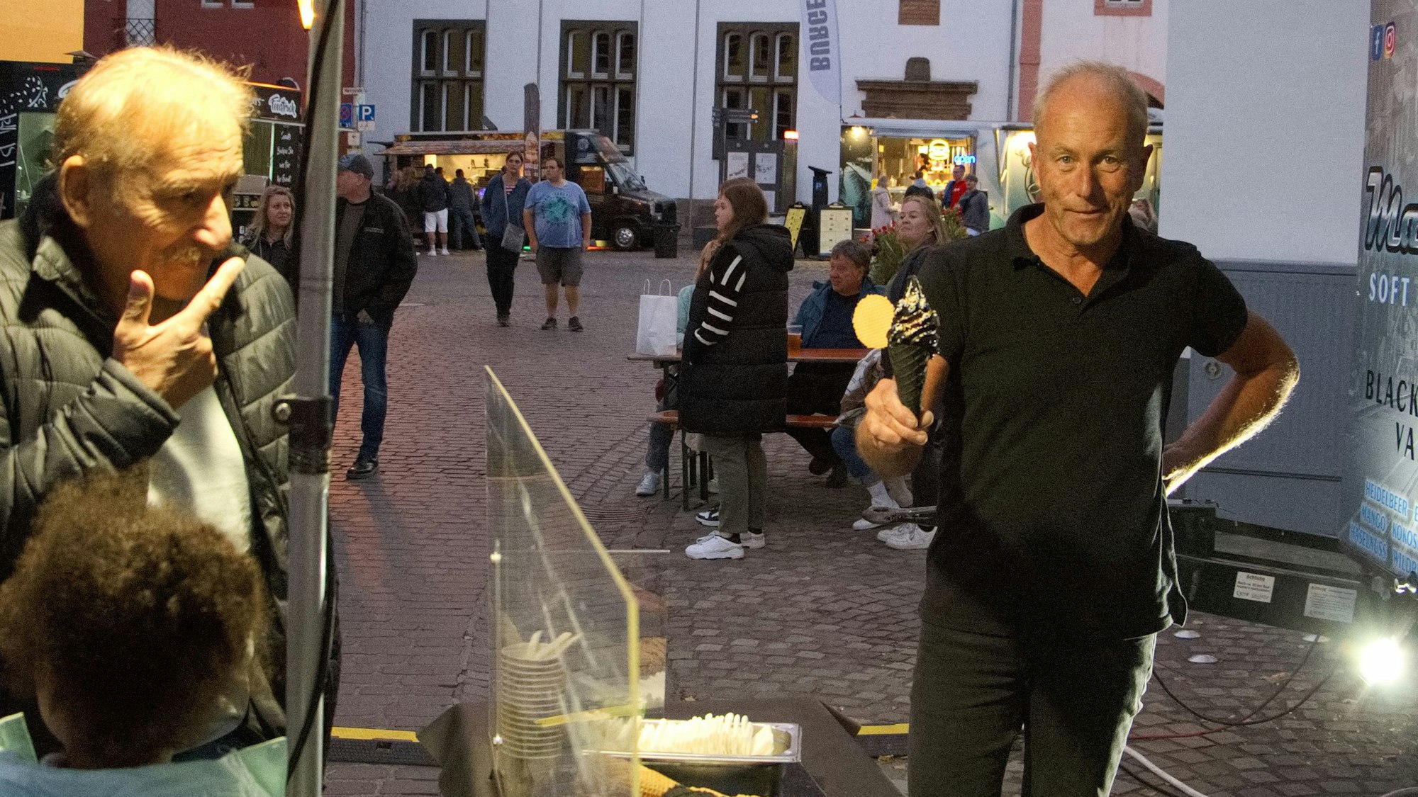 Rainer Ober hält ein schwarzes Softeis in die Kamera.