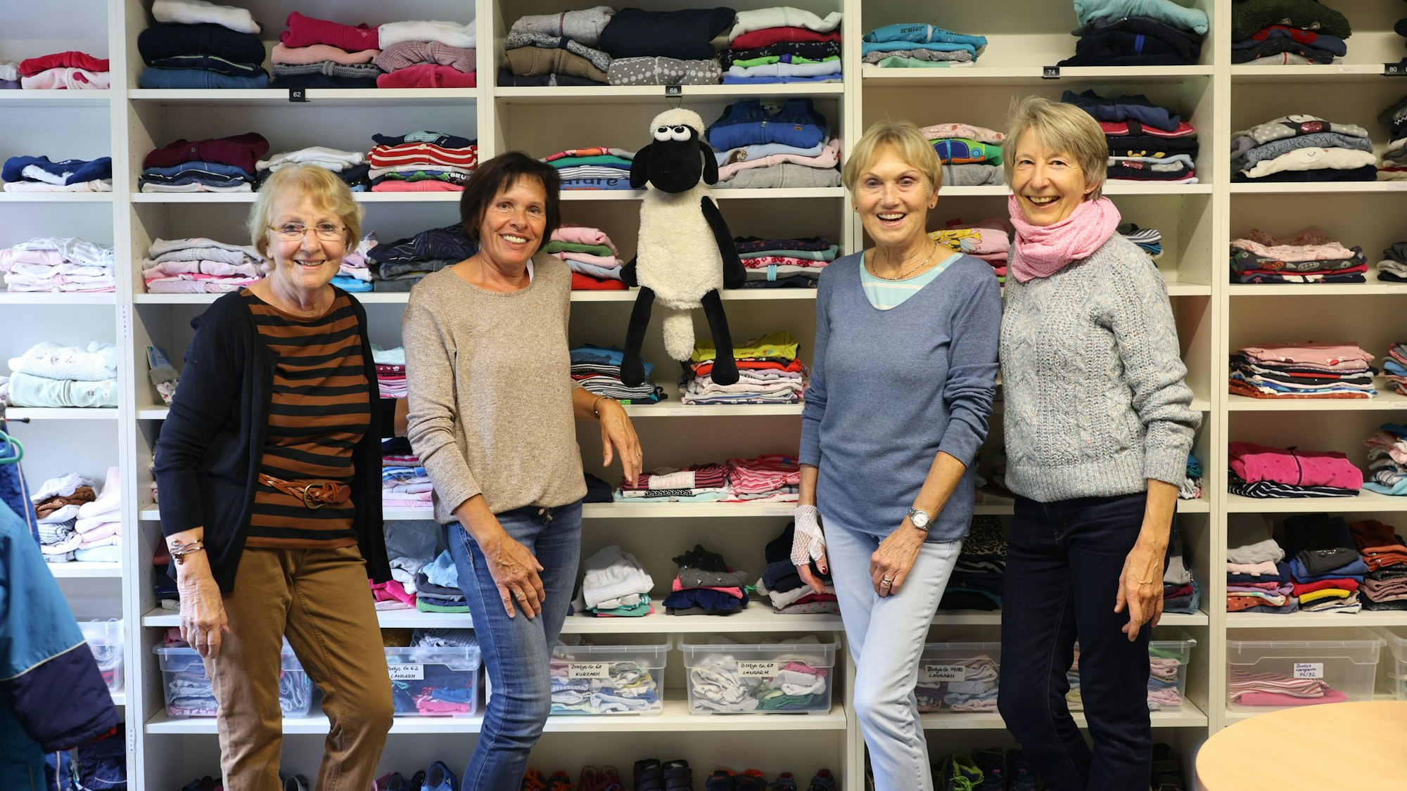 Ilona Schorn (v.l.), Jutta Plewe, Ellen Wolter und Gundi Krütt-Arnold stehen vor einem Reagl mit Kleidung darin.