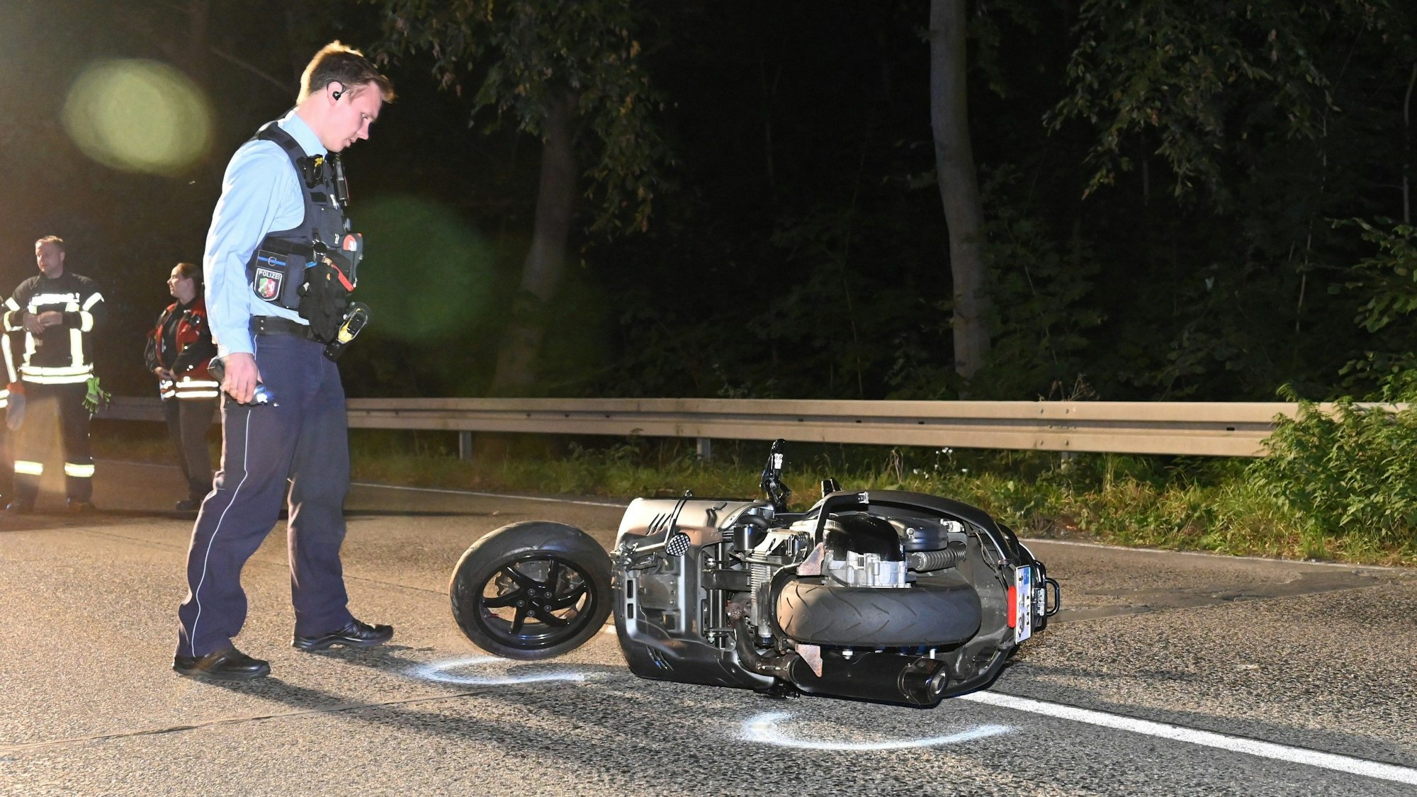 Ein Polizist steht neben einem Motorroller.