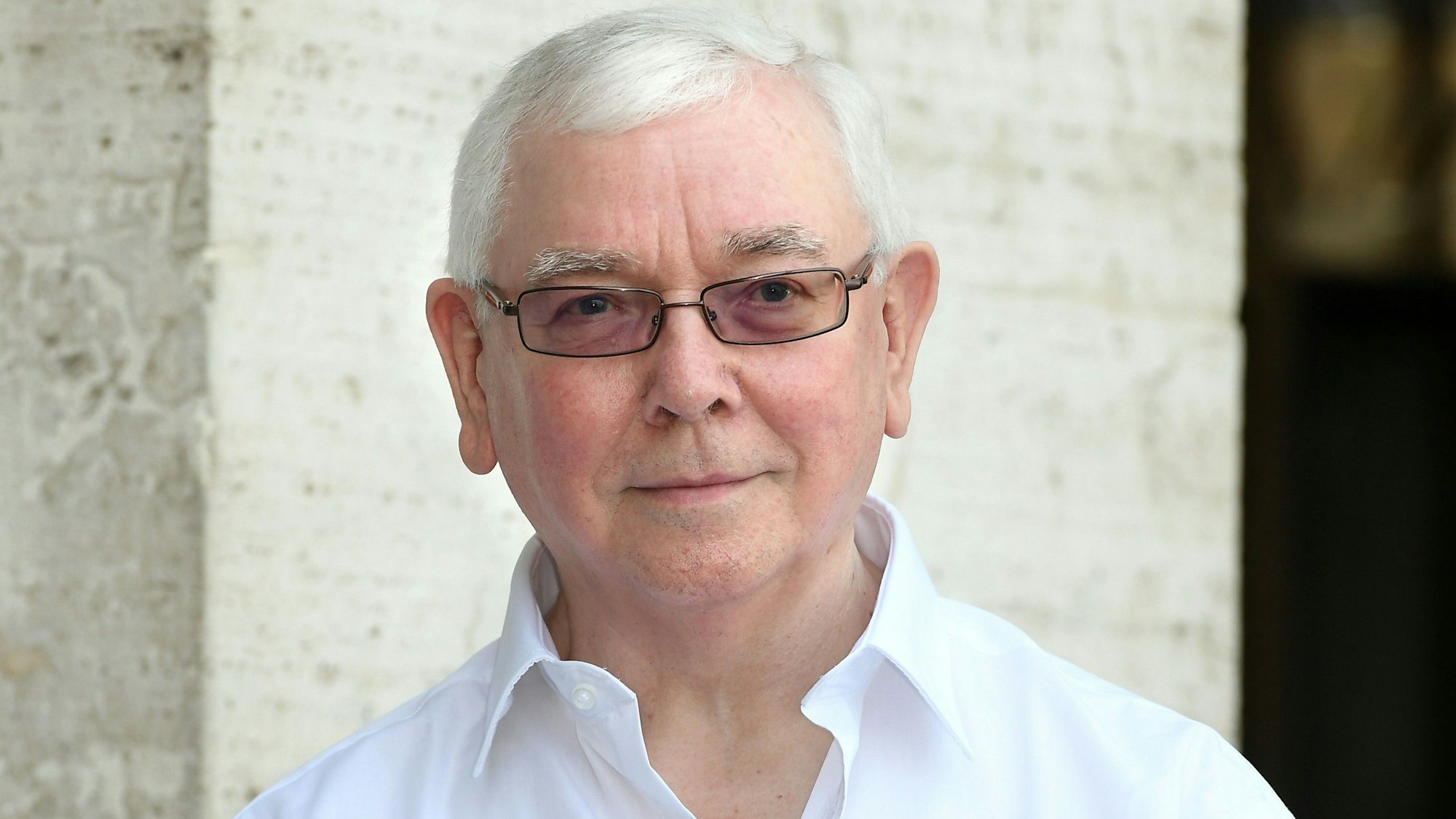 Terence Davies schaut in die Kamera, er trägt ein weißes Hemd zu seinem weißen Haar.