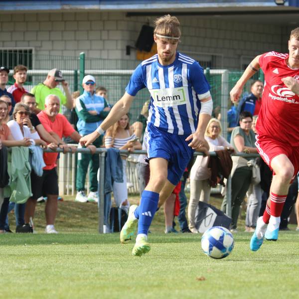 Vor vollen Rängen führen zwei Fußballer ein Laufduell.