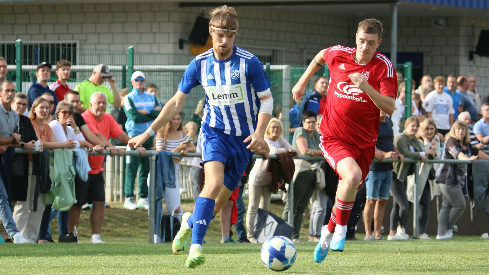 Vor vollen Rängen führen zwei Fußballer ein Laufduell.